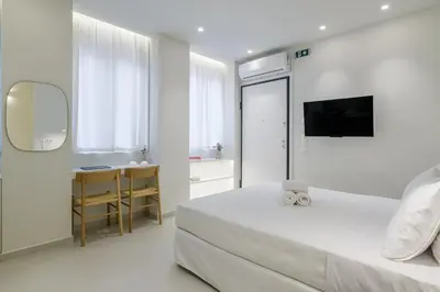 a white bedroom with a bed and a television at Ivory - Studio in Thisseio in Athens