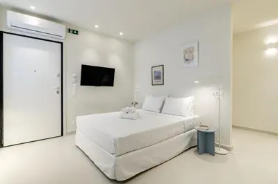 a white bedroom with a large bed and a tv at Ivory - Studio in Thisseio in Athens