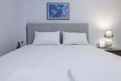 a white bed with two pillows and a picture on the wall at Modern Studio Stay in Trendy Kolonaki in Athens