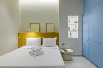 a bedroom with a white bed with a yellow headboard at Ciel - Studio in Thisseio in Athens