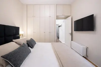 a bedroom with a large bed with a television on the wall at Luxurious Apartment at Hilton Area in Athens