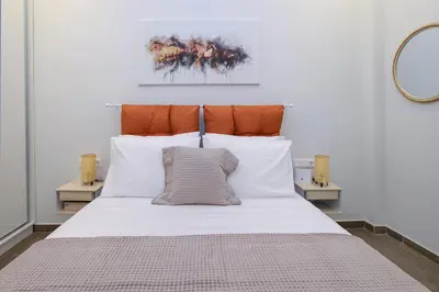 a large bed with white pillows and an orange headboard at Lilly's House in Athens