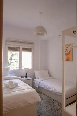 a white bedroom with two beds and a mirror at E35 by SpitiSou in Athens