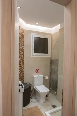 a bathroom with a toilet and a television on the wall at E35 by SpitiSou in Athens