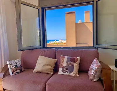 a couch with pillows sitting in front of a window at My Seaview & Beach home in Athens