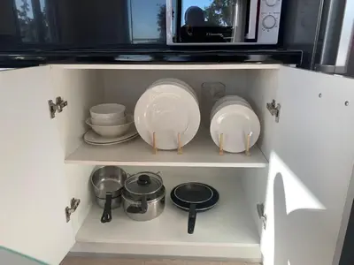 a kitchen cabinet with plates and utensils in it at My Seaview & Beach home in Athens