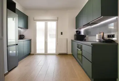 a kitchen with green cabinets and a wooden floor at 4th Floor Bright 2BR Retreat Near Acropolis in Athens