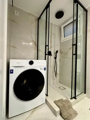 a washing machine in a bathroom with a shower at Cozy apartment in Kolonaki in Athens