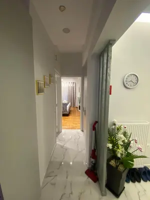 a hallway with white walls and a clock on the wall at Golden Nest Apartment in Athens