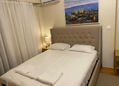 a bed in a bedroom with a painting on the wall at Acropolis Vista 3-Bedroom in Neos Kosmos in Athens