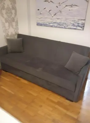 a couch sitting in a living room on a wooden floor at The Athenian Nest 2-Bedroom Apartment in Metaxou in Athens