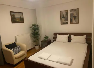 a bedroom with a large white bed and a chair at Athenas Residence 3-Bedroom Apartment in Alimos in Athens