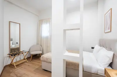 a white bedroom with a bed and a mirror at Acropolis Canvas-3BDR in Athens