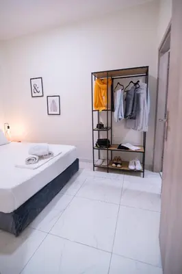 a white room with a bed and a rack of clothes at Monza in Athens