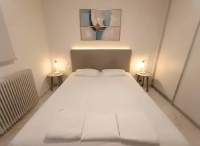a large white bed in a room with two lamps at Cozy 1-Bedroom Apartment in Pagkrati Close to Metro in Athens