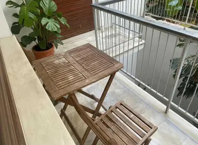 a wooden table and a chair on a balcony at Cozy 1-Bedroom Apartment in Pagkrati Close to Metro in Athens