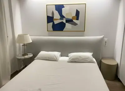 a white bed with two pillows and a painting at Athens at Your Doorstep Chic Syntagma Apartment in Athens