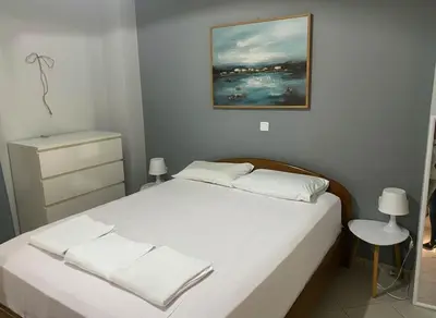 a bedroom with a bed with white sheets and a painting at Urban Comfort Stay in Peristeri in Athens