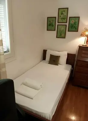 a small bedroom with a white bed and a desk at Family-Friendly Comfort in the Heart of Koukaki in Athens
