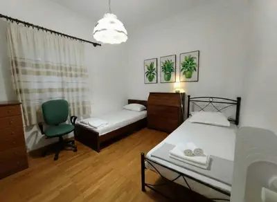 a bedroom with two beds and a green chair at Family-Friendly Comfort in the Heart of Koukaki in Athens