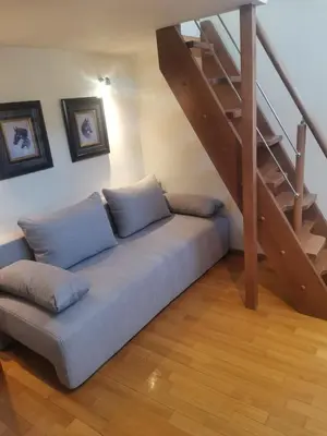 a couch with pillows sitting under a staircase at Luxurious maisonette 4 metro stops to Acropolis in Athens