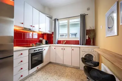a kitchen with red walls and white cabinets and a dishwasher at Athens Nala in Athens