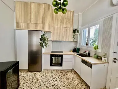 a kitchen with white cabinets and a stainless steel refrigerator at Athens Classic 2- Bedroom Apartment in Athens