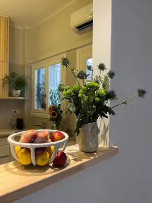 a bowl of fruit on a table with a vase of flowers at Athens Classic 2- Bedroom Apartment in Athens