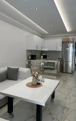 a living room with a white table and a kitchen at Cozy, Quiet & Modern Apartment in Athens