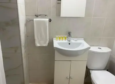 a white bathroom with a toilet and a sink at Modern 1BD Kallithea Home with Patio in Athens