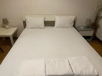a large bed with white sheets and pillows at Relaxing Flat by Stavros Niarchos Park in Athens