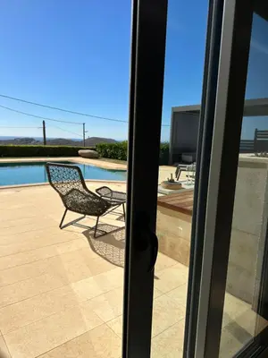 a sliding glass door with a chair and a pool at BonVilla Seaview Oasis in Anavissos