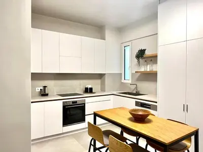 a kitchen with white cabinets and a wooden table at New 1BR Apt modern and light in Athens