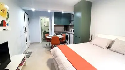 a bedroom with a bed and a table and a kitchen at Downtown & Cozy Kolonaki in Athens