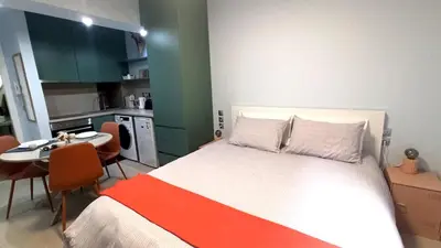 a bedroom with a bed and a table and a kitchen at Downtown & Cozy Kolonaki in Athens