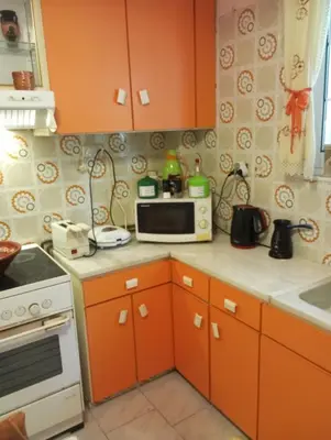 a kitchen with orange cabinets and a microwave at ΕΥΧΑΡΙΣΤΗ Διαμονη in Athens