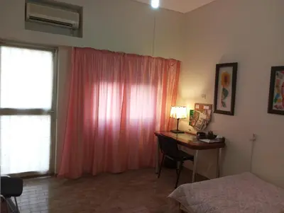 a bedroom with a desk and a window with a pink curtain at ΕΥΧΑΡΙΣΤΗ Διαμονη in Athens