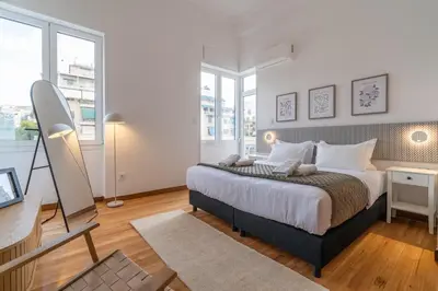 a bedroom with a large bed in a room with windows at Belle Étage 4BD 3BA Apt Kypseli Athens in Athens