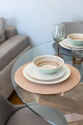 a glass table with two plates and a wine glass at HELIOS sunny comfortable apartment in Athens