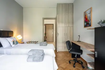 a bedroom with two beds and a desk and a chair at HELIOS sunny comfortable apartment in Athens