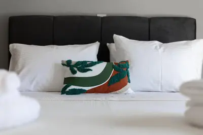a bed with white pillows and a pillow on it at HELIOS sunny comfortable apartment in Athens