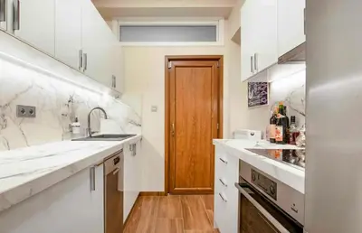 a kitchen with white counters and a wooden door at Charming Flat with Traditional & Elegant Style in Piraeus