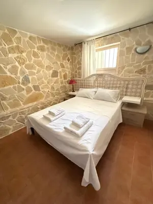 a bedroom with a large bed in a stone wall at Laguna in Ayía Paraskeví