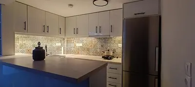 a kitchen with white cabinets and a black refrigerator at CityZen Apartment in Athens