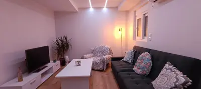 a living room with a black couch and a tv at CityZen Apartment in Athens