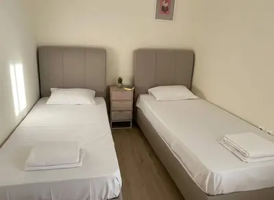 two beds in a small room with white sheets at The Athenian Escape Elegant 2BR Apt in Galatsi in Athens