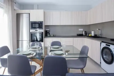 a kitchen with a glass table and chairs and a kitchen with a dishwasher at Brand New Spacious 3 Bd Home in Trendy Kipseli in Athens