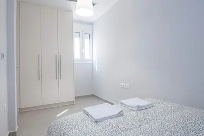 a white bedroom with a bed and a white cabinet at Brand New Spacious 3 Bd Home in Trendy Kipseli in Athens