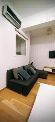 a black couch sitting in a living room at Cosy apartment close to the railway & metro stations in Athens