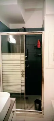 a shower with a glass door in a bathroom at Cosy apartment close to the railway & metro stations in Athens